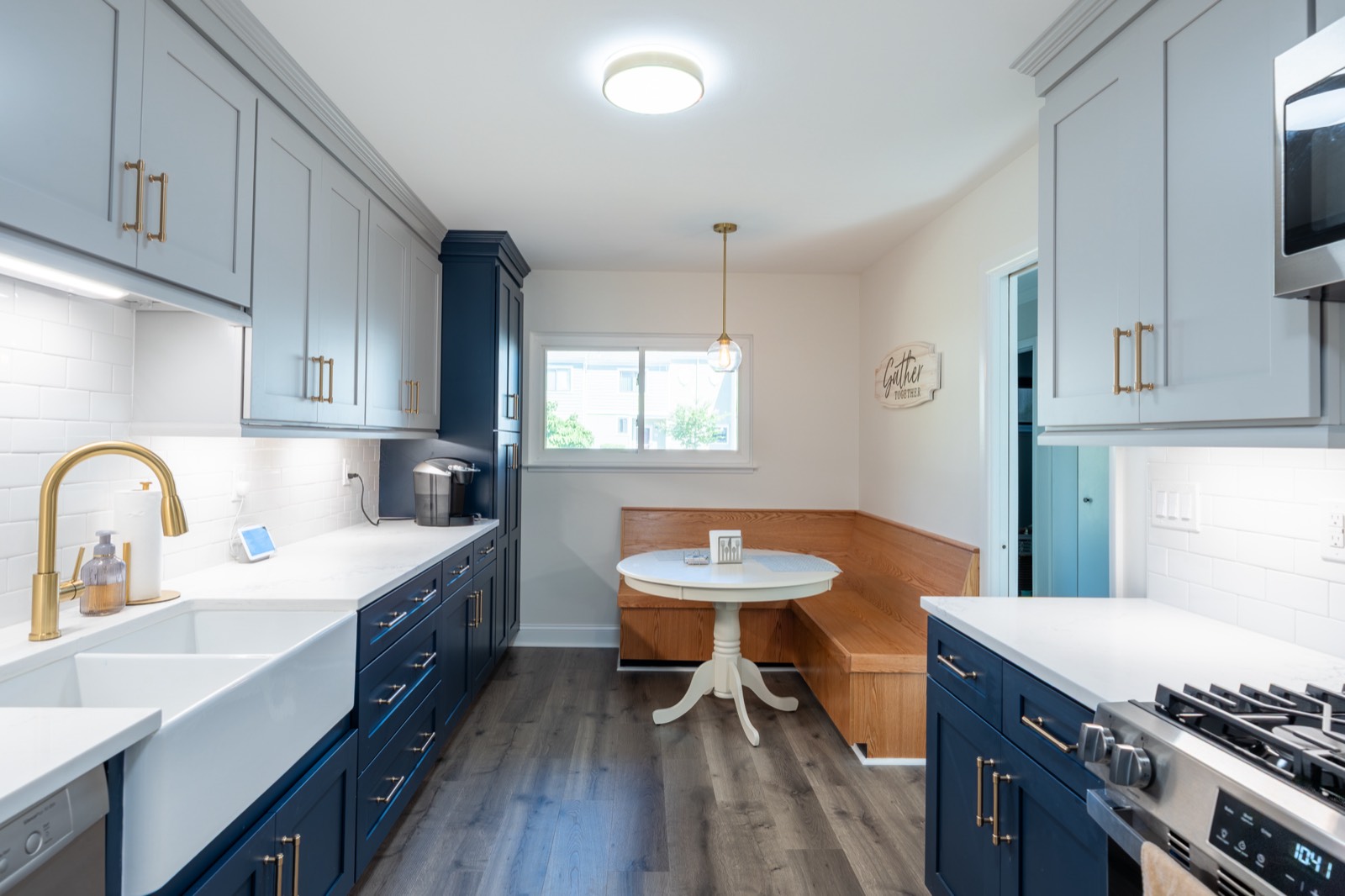 Galley kitchen with navy cabinets, farmhouse sink and breakfast nook