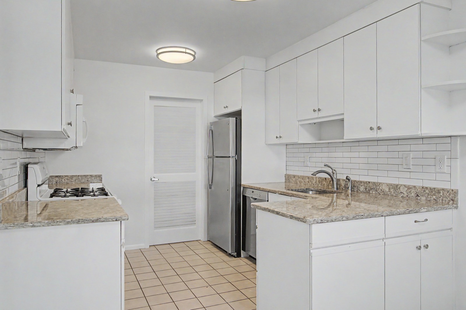 Before: the same galley kitchen with white cabinets and tile floor