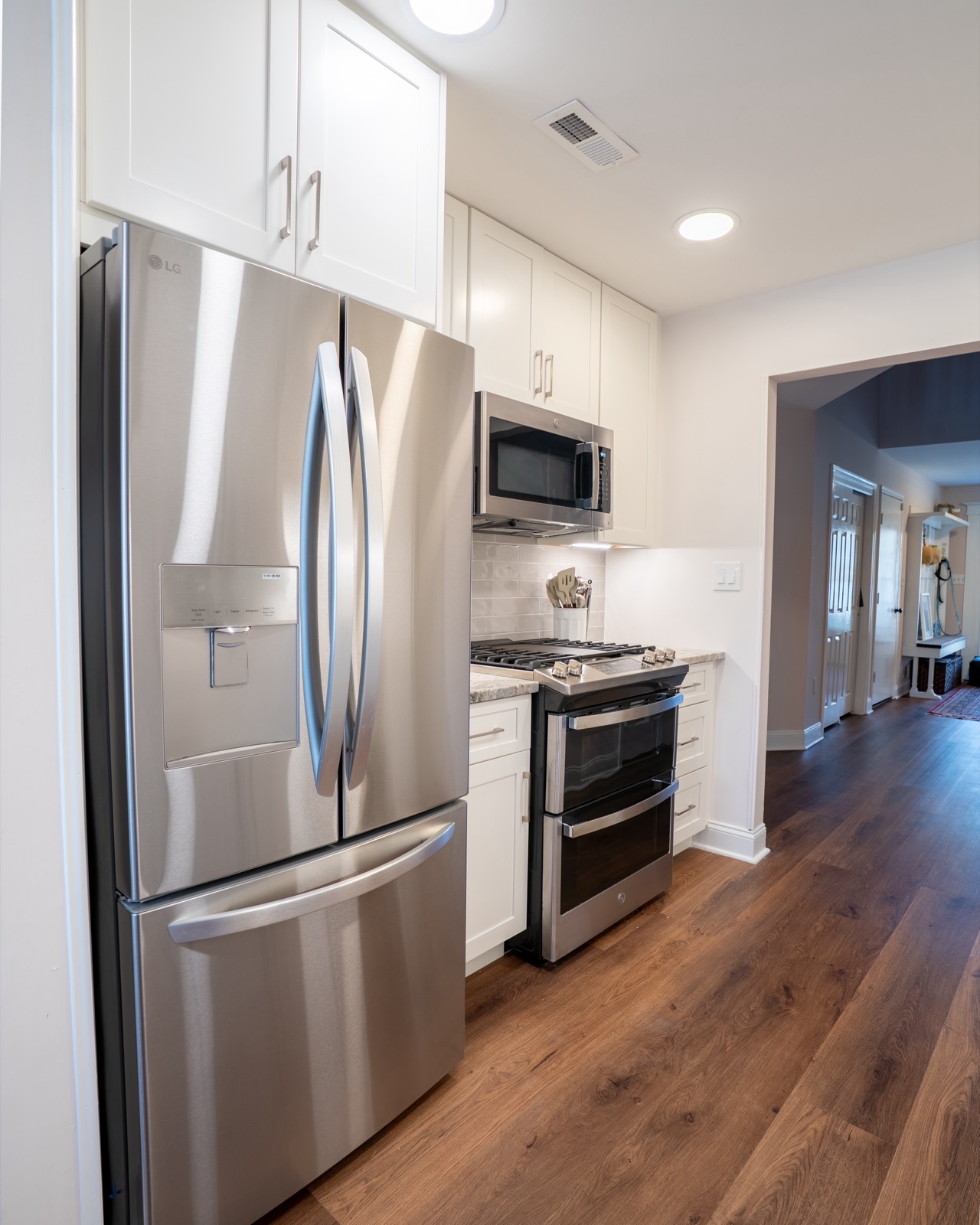 White kitchen with grey backsplash and stainless appliances