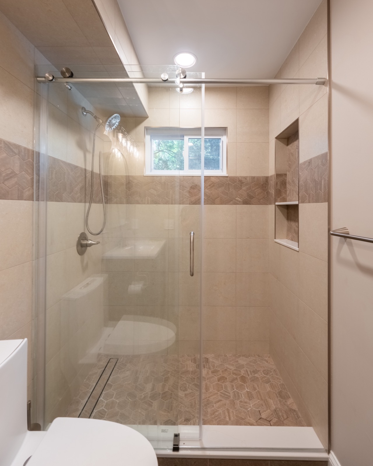 Walk-in shower with glass door and tile niche