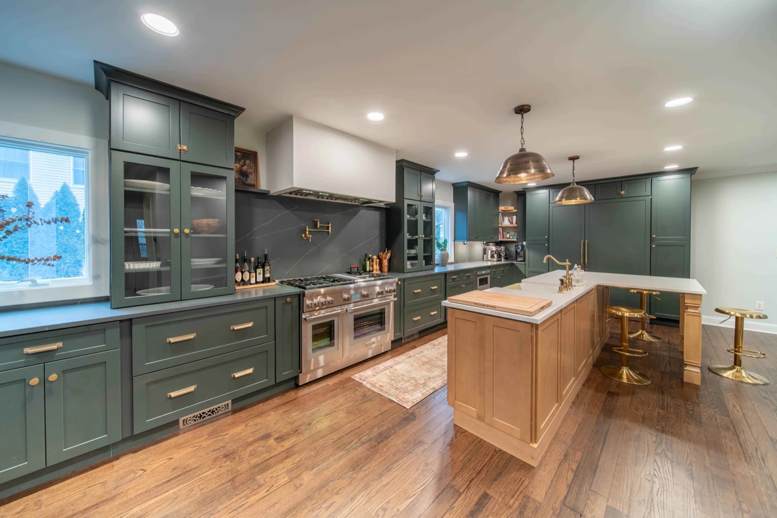 Green shaker kitchen with a white-oak island and gold pendants
